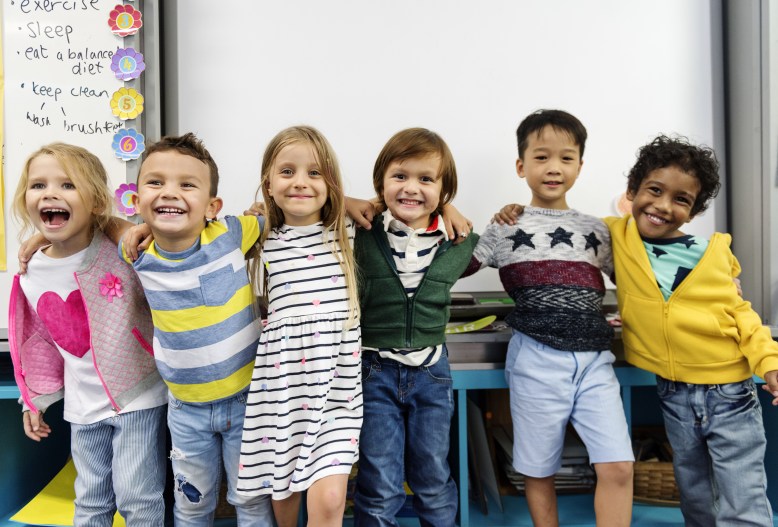Group of diverse kindergarten students standing together in classroom