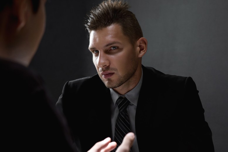 Detective interviewing suspect in dark interrogation room
